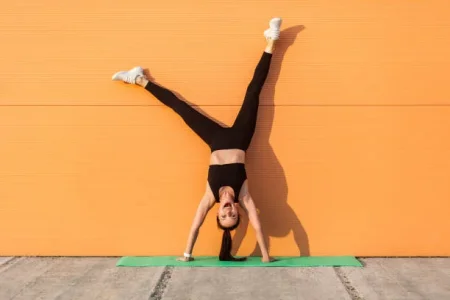 overjoyed-excited-girl-with-perfect-athletic-body-in-tight-sportswear-doing-yoga-handstand.webp